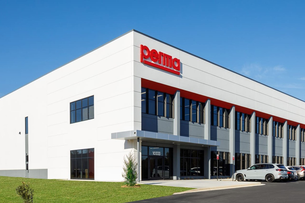 Modern white industrial building with red Perma logo signage and blue-gray architectural elements