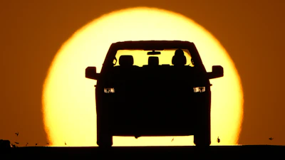 Car silhouette against a large golden sunset sky