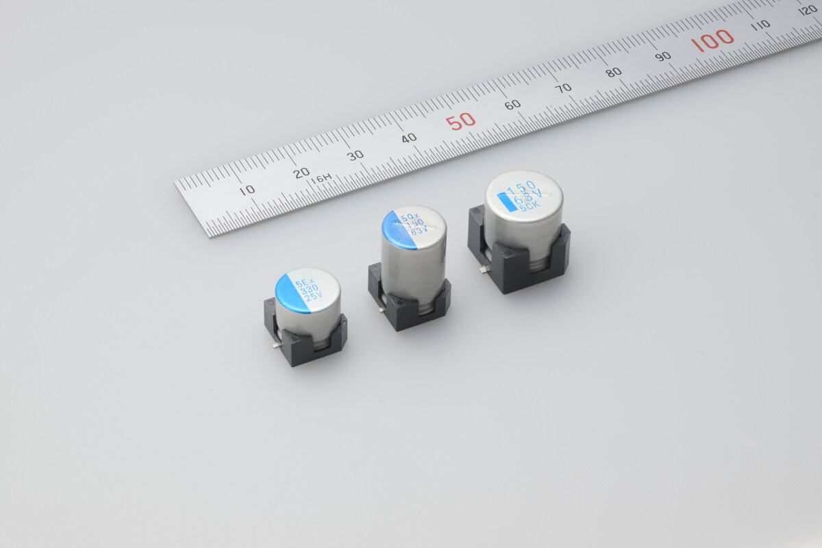 Three surface-mount electronic components with blue labels displayed next to a measuring ruler for size comparison