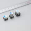 Three surface-mount electronic components with blue labels displayed next to a measuring ruler for size comparison