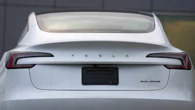 White Tesla sedan rear view with illuminated taillights and dual motor badge