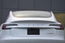 White Tesla sedan rear view with illuminated taillights and dual motor badge