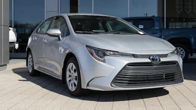 Silver Toyota Corolla sedan parked at dealership with glass storefront backdrop
