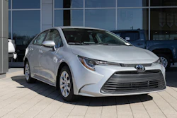 Silver Toyota Corolla sedan parked at dealership with glass storefront backdrop