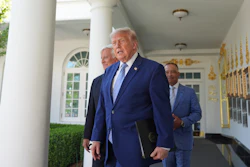 Three men in business suits walking through a white columned corridor with decorative gold accents