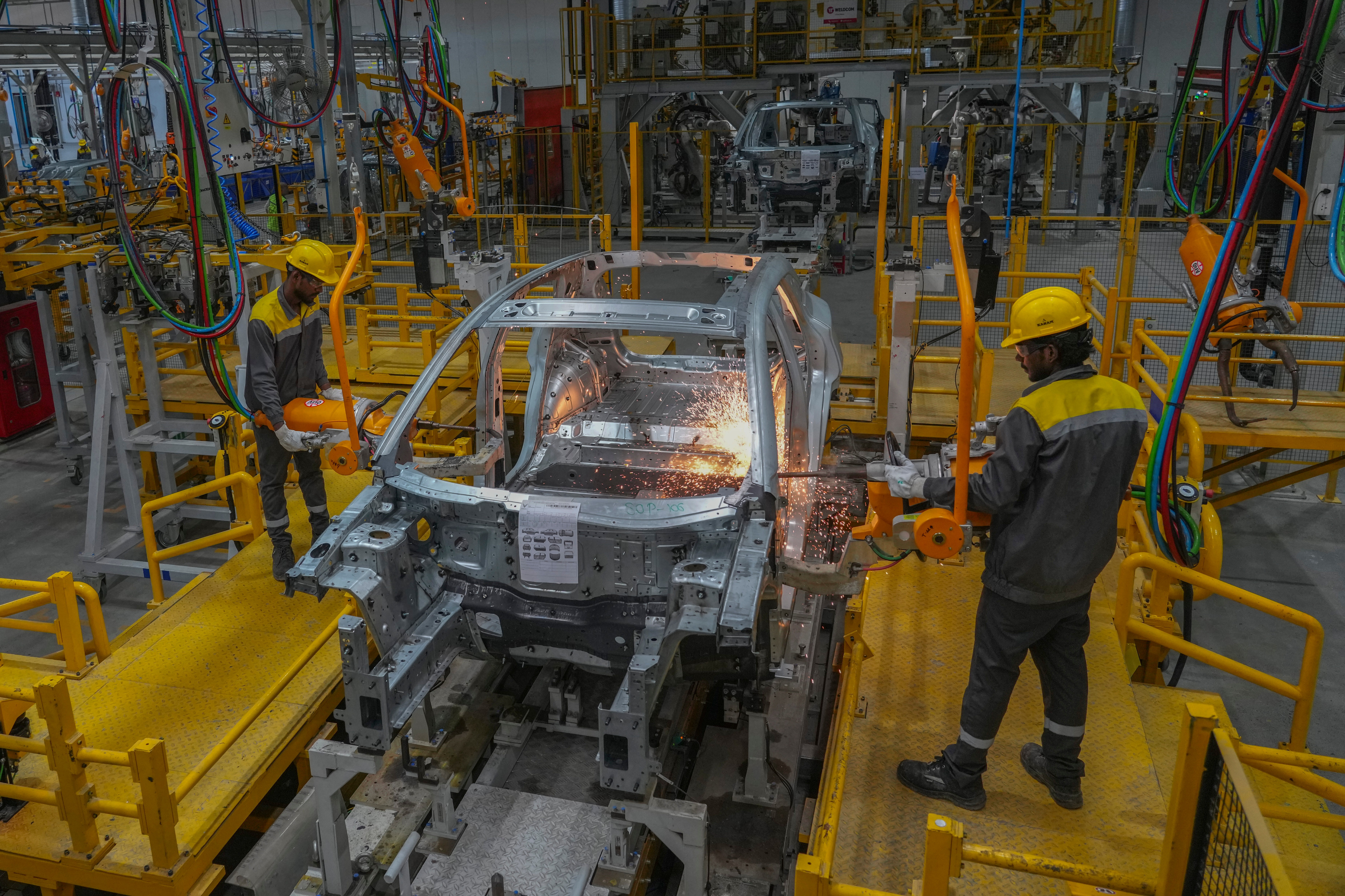 Automotive manufacturing facility with welding robot performing metal work on vehicle body frame