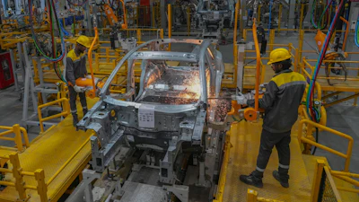 Automotive manufacturing facility with welding robot performing metal work on vehicle body frame