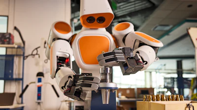 Orange and white humanoid robot with articulated hands in a workshop laboratory setting