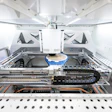 Interior view of automated laboratory analyzer with mechanical components, tracks, and robotic arm system