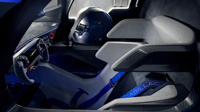 Cadillac racing car interior with blue and gray racing seats, steering wheel, and helmet