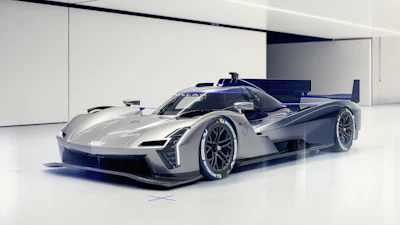 Silver and blue high-performance race car with aerodynamic design and exposed cockpit displayed in minimalist white studio setting