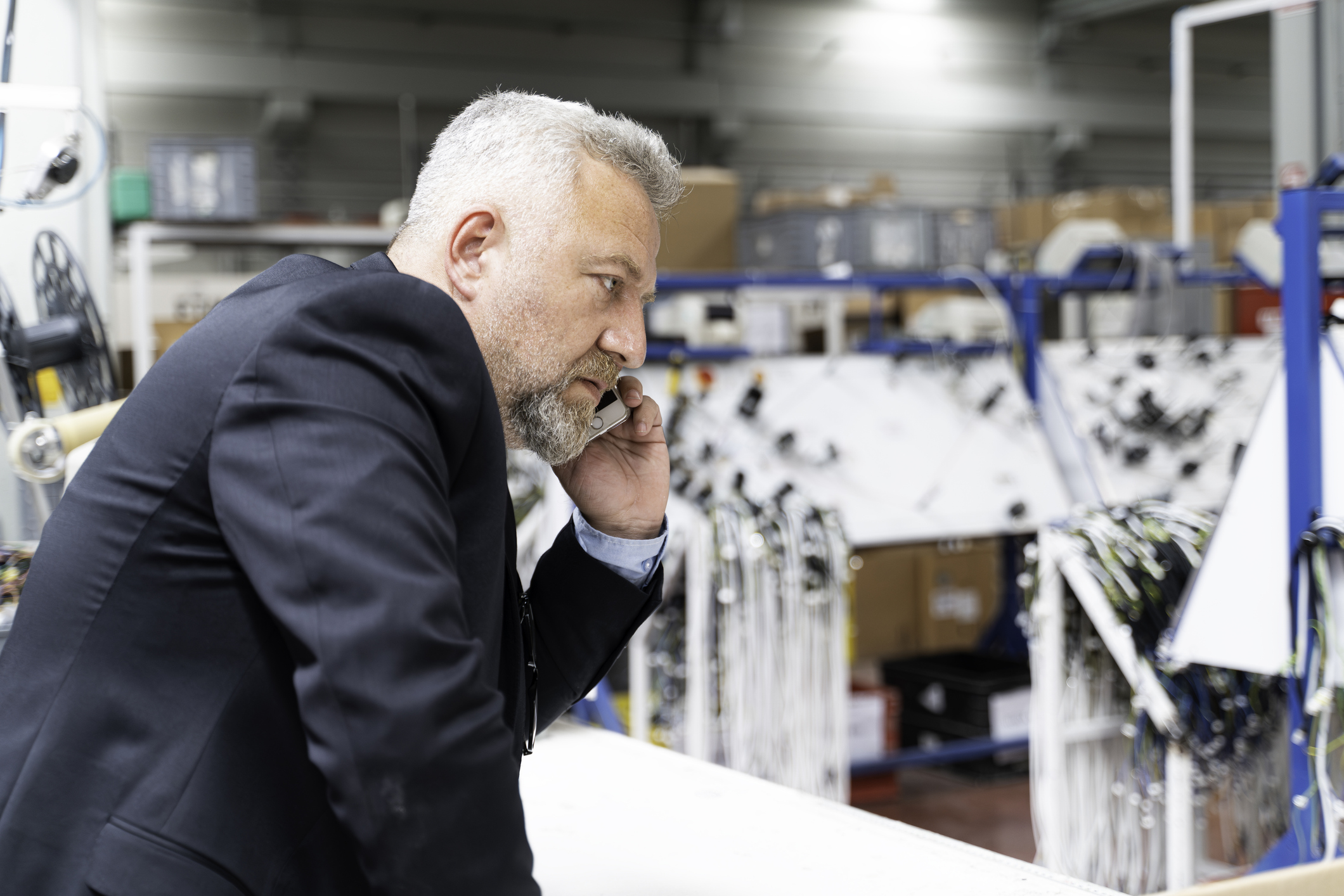 Businessman in navy blazer examining equipment in industrial warehouse facility