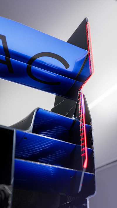 Modern blue cylindrical structure with black geometric accents and red LED lighting against cloudy sky