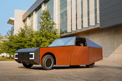 Orange and black concept vehicle with geometric design parked in front of modern building