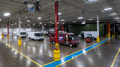 Industrial warehouse facility with service vehicles, red support columns, and yellow safety barriers on polished concrete floor