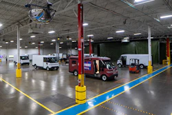 Industrial warehouse facility with service vehicles, red support columns, and yellow safety barriers on polished concrete floor