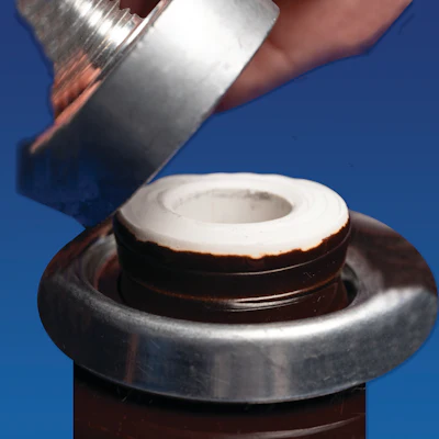Hand pouring coconut milk from a bottle into a fresh coconut half against blue background