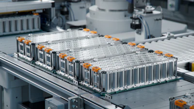Industrial battery modules with orange hardware arranged on assembly line in manufacturing facility