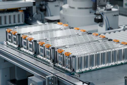Industrial battery modules with orange hardware arranged on assembly line in manufacturing facility