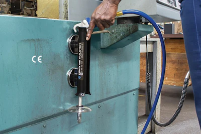 Worker operating hydraulic gauge valve on turquoise industrial machinery with blue hose attachment