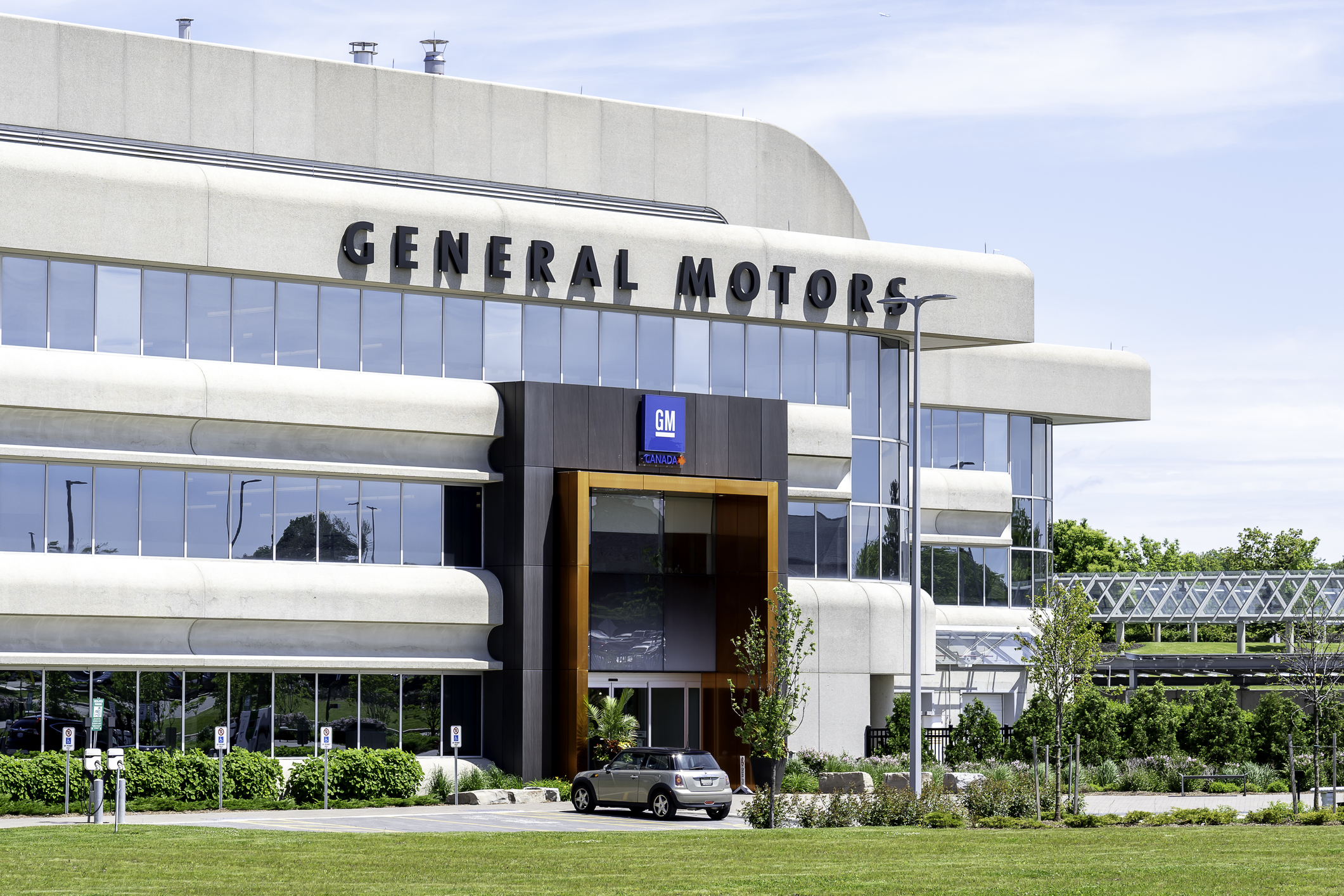 General Motors corporate headquarters building with white facade, horizontal bands, and GM logo signage on entrance