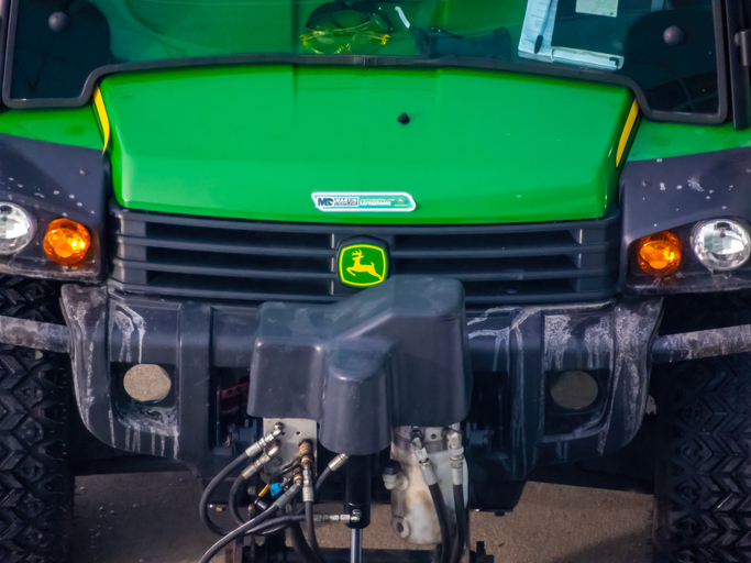 Green John Deere tractor front view with iconic yellow and green leaping deer logo on grille
