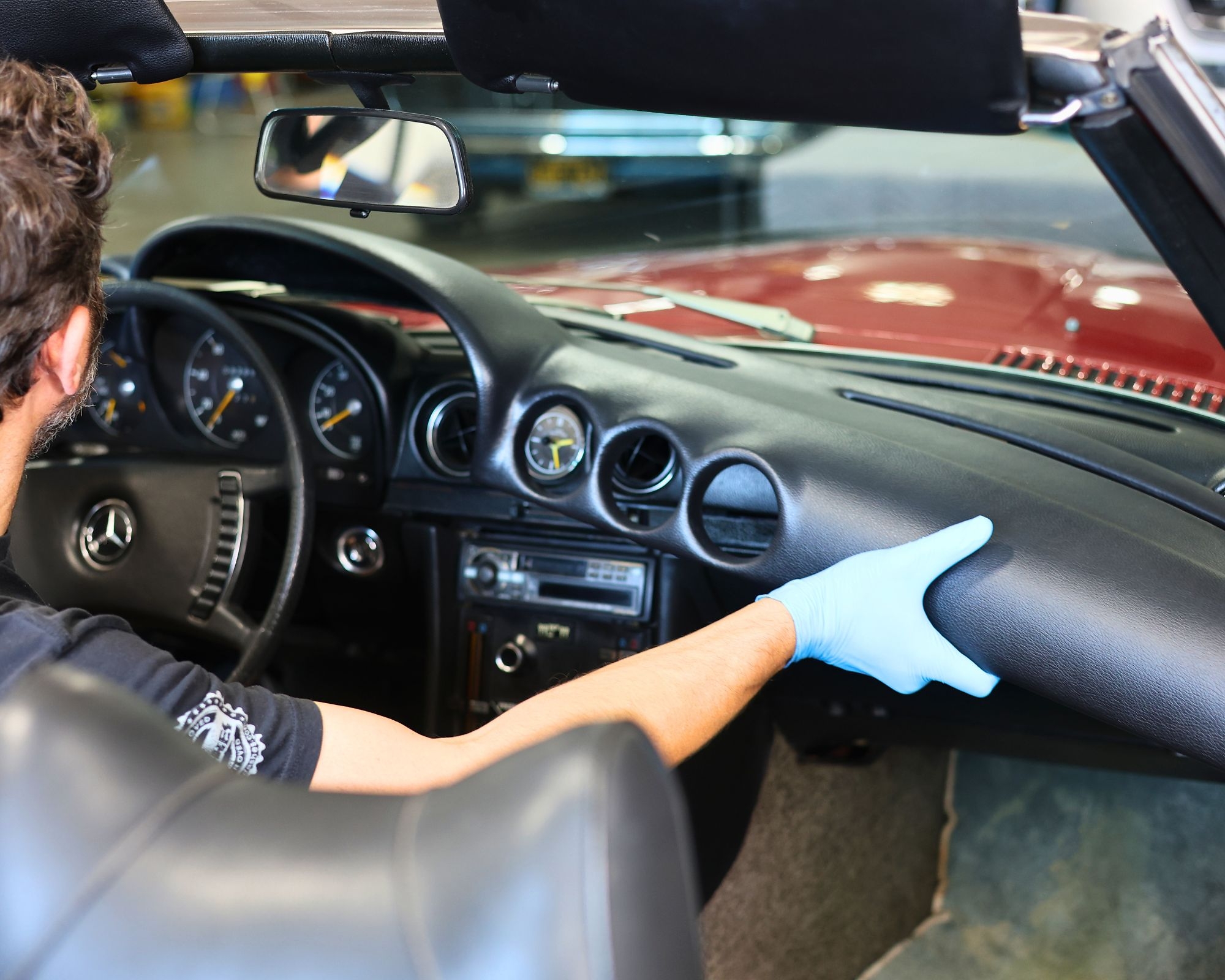 Person cleaning Mercedes-Benz convertible dashboard with blue microfiber cloth