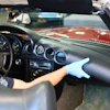 Person cleaning Mercedes-Benz convertible dashboard with blue microfiber cloth