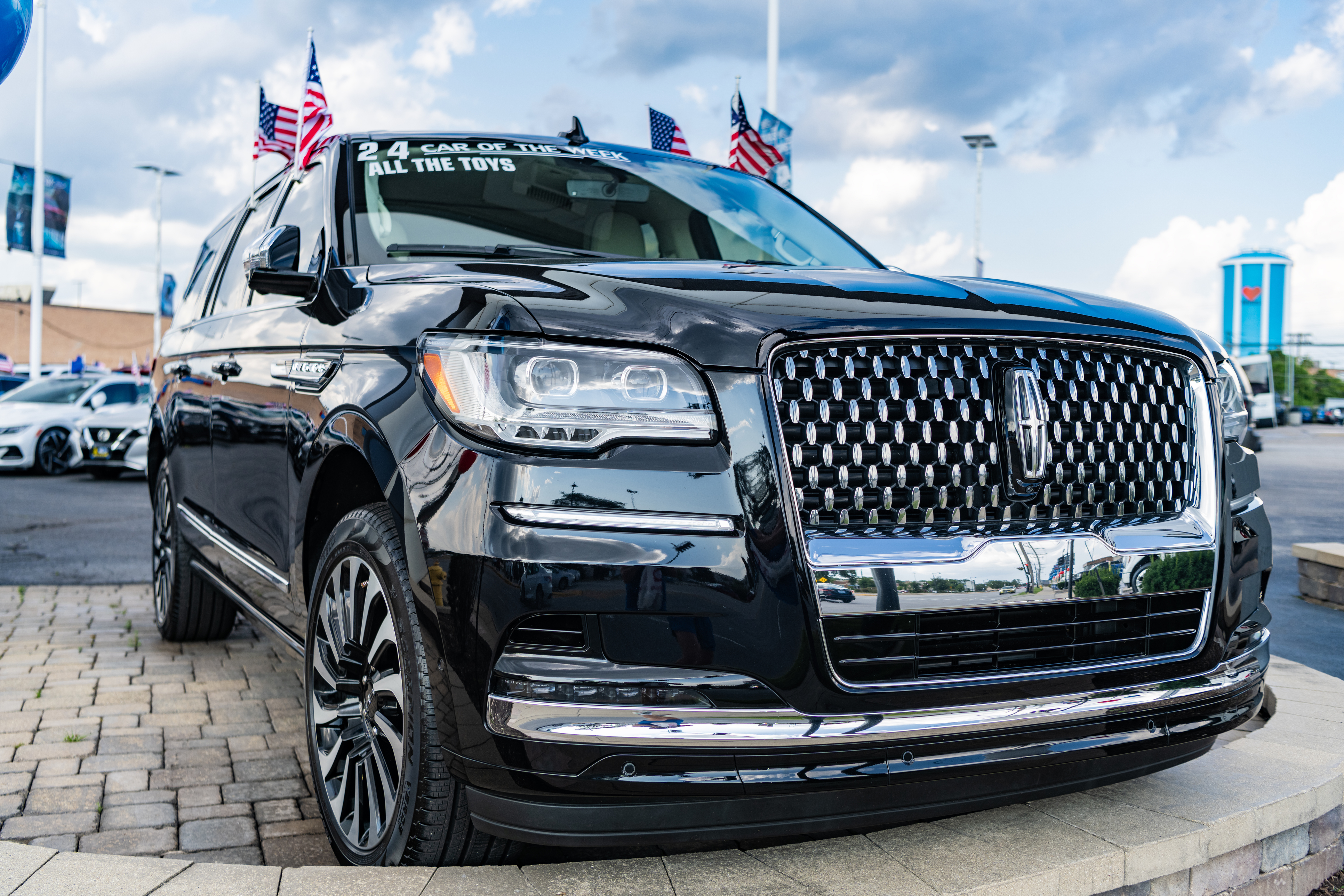 Black Lincoln Navigator SUV displayed at dealership with American flags on roof