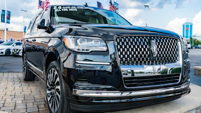 Black Lincoln Navigator SUV displayed at dealership with American flags on roof