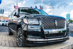 Black Lincoln Navigator SUV displayed at dealership with American flags on roof