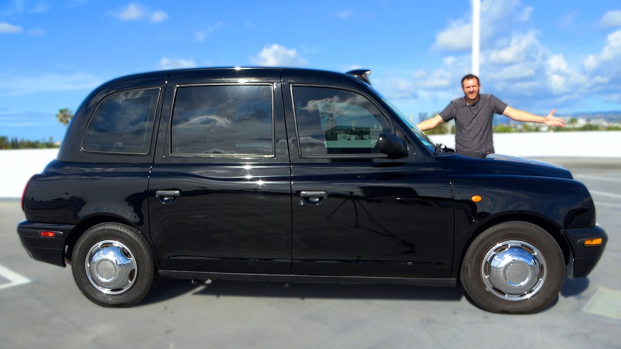 Black London taxi cab with person standing beside it on a sunny day