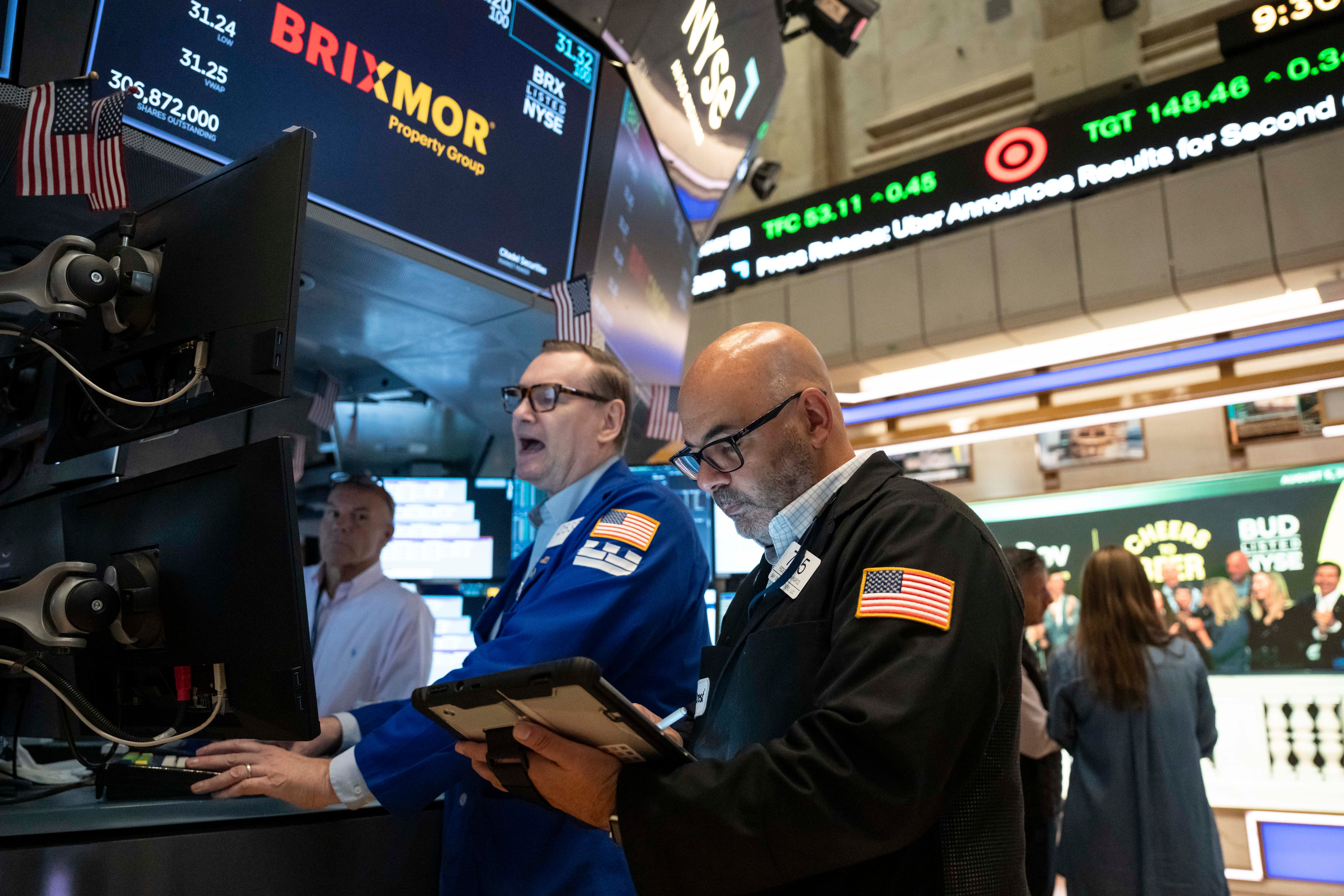 Traders monitor stock market data on the NYSE trading floor with BRIXMOR ticker visible on overhead displays