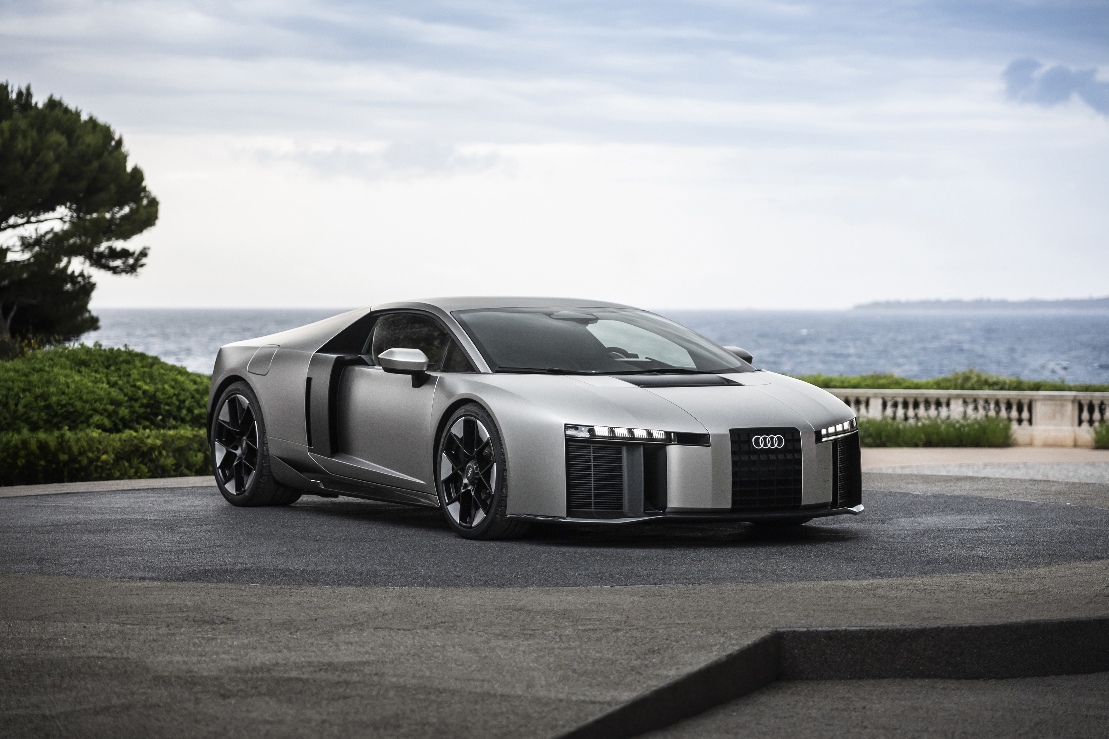Silver Audi R8 sports car with open door parked on coastal overlook with Mediterranean sea view