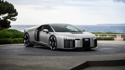 Silver Audi R8 sports car with open door parked on coastal overlook with Mediterranean sea view