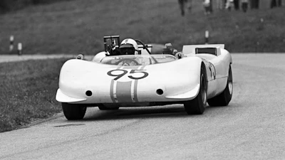 Vintage white race car number 95 with racing stripes driving on a track in black and white
