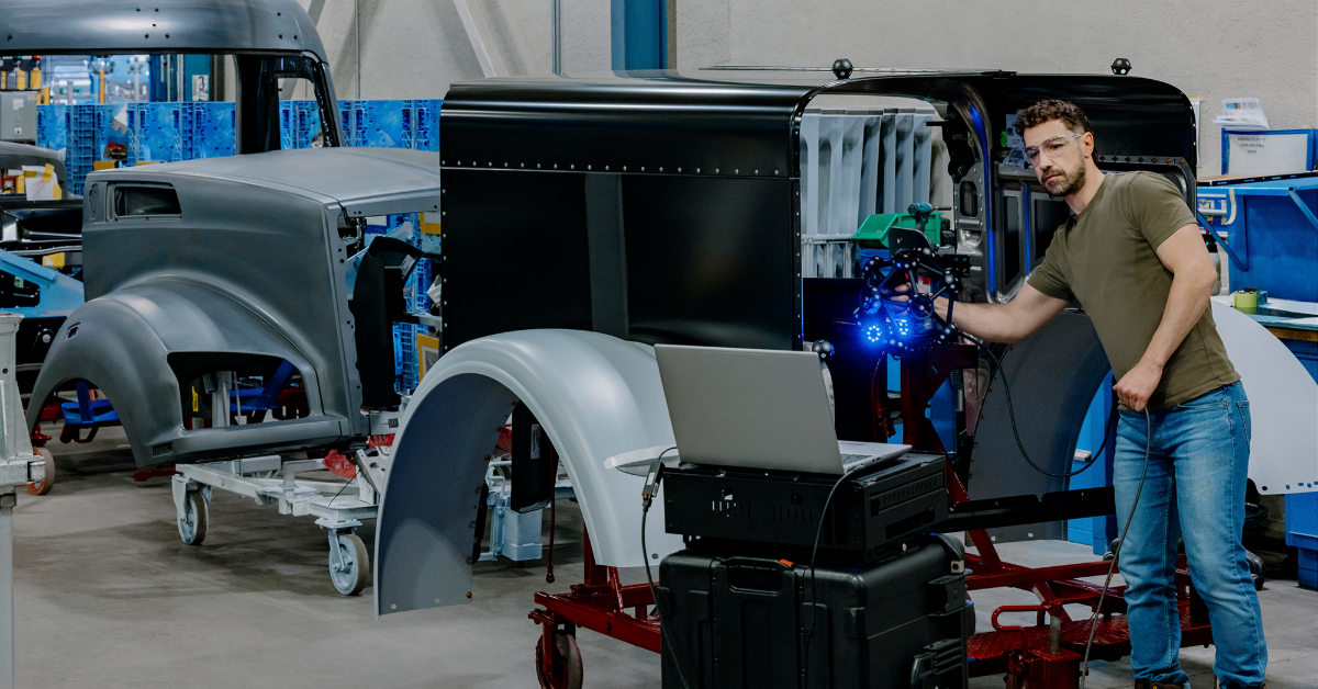 Technician assembling vehicle components in industrial workshop with machinery and parts visible