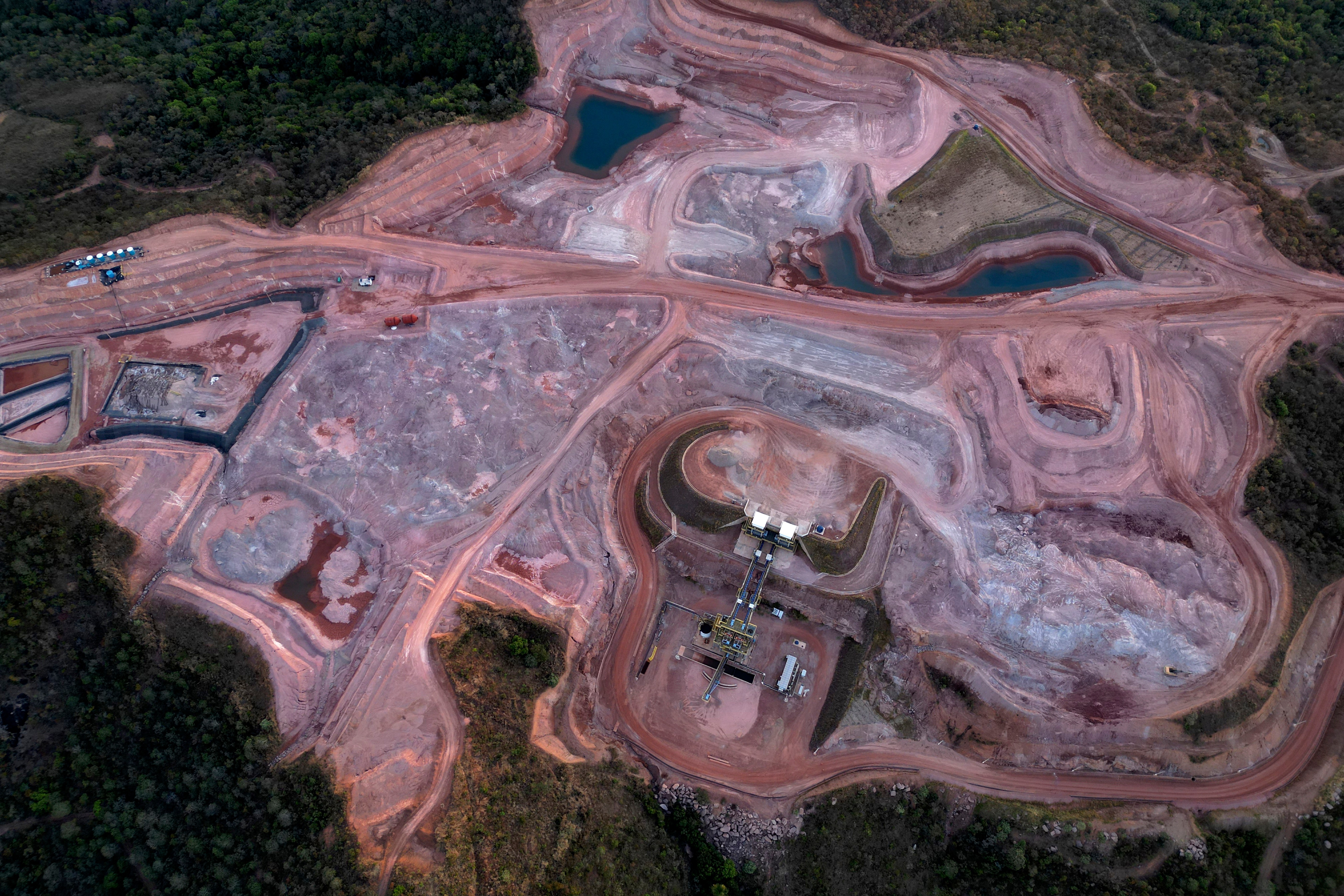 Aerial view of active mining operation with excavation equipment, pit lakes, and cleared terrain surrounded by forest