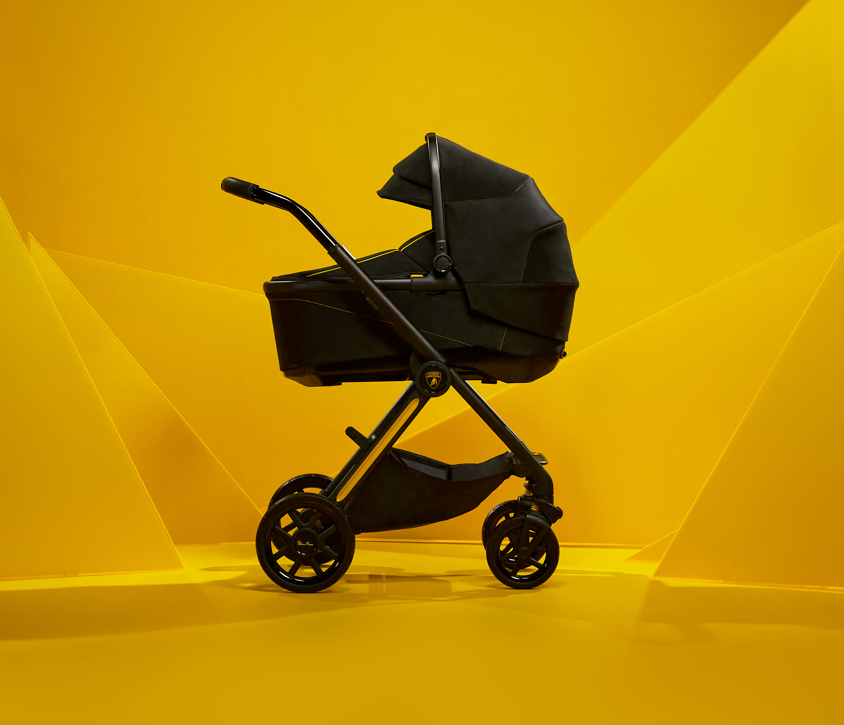 Black luxury baby stroller with gold accents on vibrant yellow background