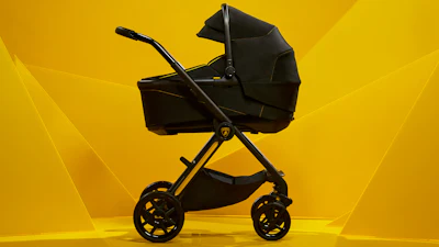 Black luxury baby stroller with gold accents on vibrant yellow background