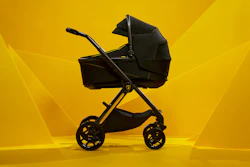 Black luxury baby stroller with gold accents on vibrant yellow background