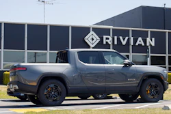 Rivian R1T electric truck parked in front of Rivian corporate building with logo signage