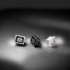 Three mechanical keyboard switches in black, white, and translucent variants displayed on a neutral surface with studio lighting