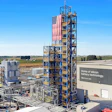 Industrial silicon battery technology manufacturing facility with tall tower and American flag in rural landscape