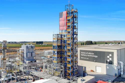 Industrial silicon battery technology manufacturing facility with tall tower and American flag in rural landscape