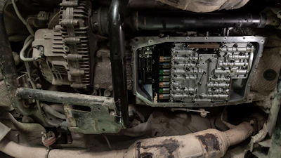 Engine compartment showing alternator, ECU module, and wiring harness in a vehicle