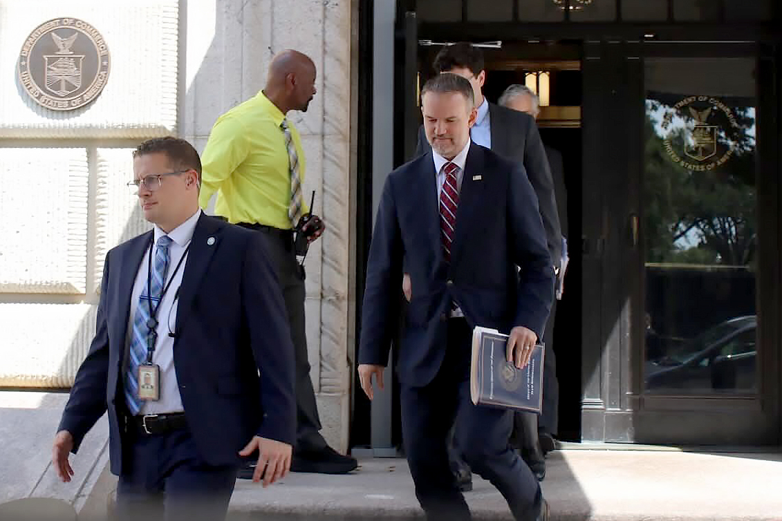 Government officials exiting federal building with official seal visible on entrance wall