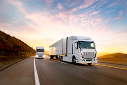 Two white Hyundai trucks driving on a highway during golden hour with mountains in background