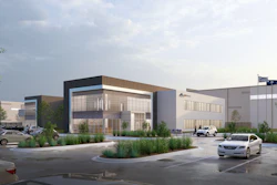 Modern industrial facility complex with contemporary architecture, parking area, and landscaping under cloudy sky