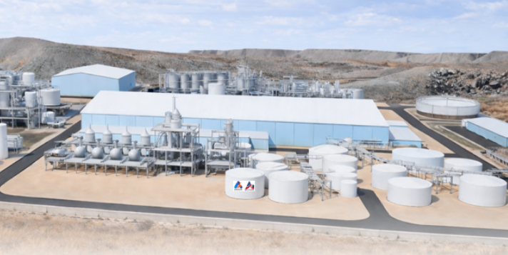Industrial processing plant with large storage tanks, manufacturing buildings, and equipment in arid landscape